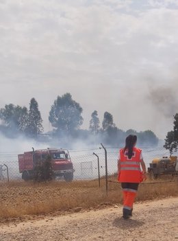 Una trabajadora de Cruz Roja y un vehículo del Infoex en el incendio declarado en la urbanización Los Rostros en Badajoz.