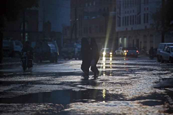 Archivo - 23 July 2021, Yemen, Sanaa: Yemeni women cross a flooded street after heavy rains in Sanaa. At least fourteen people have been killed by flooding in Yemen after nonseasonal rainstorms hit parts of the country, security officials said. Photo: H