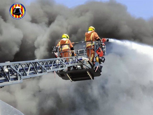 Dos bomberos trabajan en el incendio de una nave industrial en Riba-roja