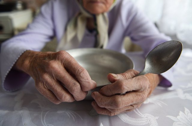 Archivo - Manos de mujer mayor sujetando un plato de comida. Anciana. Comer. Desnutrición.
