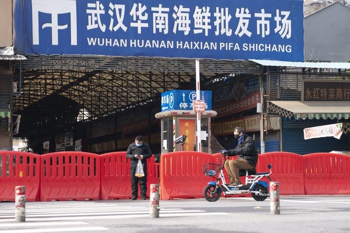 Archivo - Dos ciudadanos pasan por la entrada del mercado de mariscos Huanan en Wuhan, provincia de Hubei, en el centro de China, el 29 de enero.