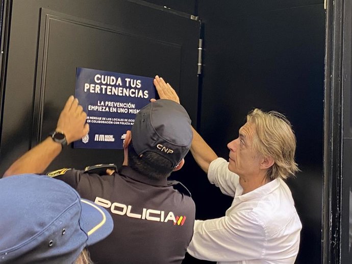 Un agente de la Policía Nacional junto con el presidente de la Plataforma por el Ocio, Javier Olmedo, pegando un cartel de la campaña "Cuida tus pertenencias" en una discoteca de Madrid.