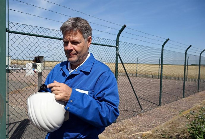 28 July 2022, Saxony-Anhalt, Bad Lauchstaedt: German Minister for the Economy and Climate Protection Robert Habeck puts on a white helmet during his visit to VNG Gasspeicher GmbH before touring a cavern storage facility. Underground hydrogen storage in 