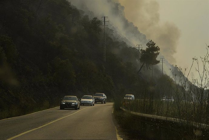 Varios coches desalojan la zona debido al incendio en el municipio, a 18 de julio de 2022, en O Barco de Valdeorras, Ourense, Galicia (España). La superficie arrasada por los principales incendios registrados en Galicia ya supera las 9.000 hectáreas, se