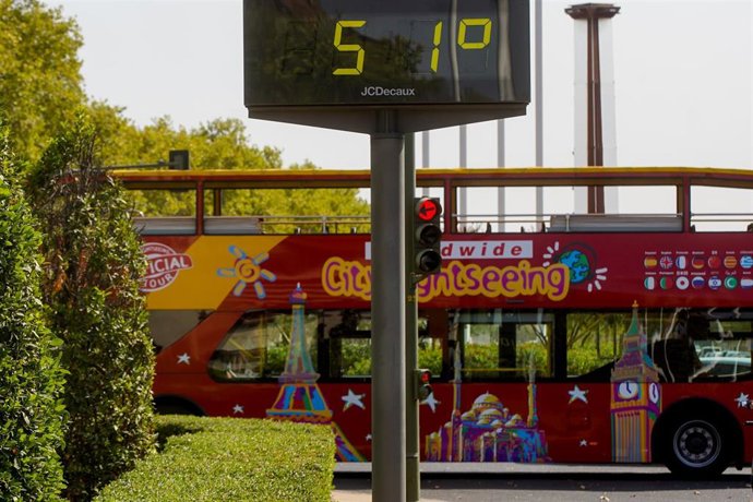 Un autobús turístico pasa sin pasajeros delante de un termómetro que marca 51 en otro día con altas temperaturas en la capital andaluza, en foto de archivo.