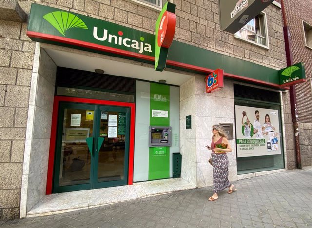 Una persona pasa por delante de una oficina de Unicaja, a 18 de julio de 2022, en Madrid (España).