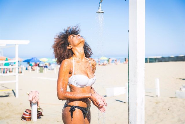 Archivo - Mujer usando una ducha en la playa.