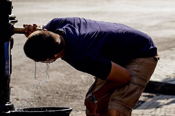 Un joven bebe en una fuente para combatir las elevadas temperaturas.