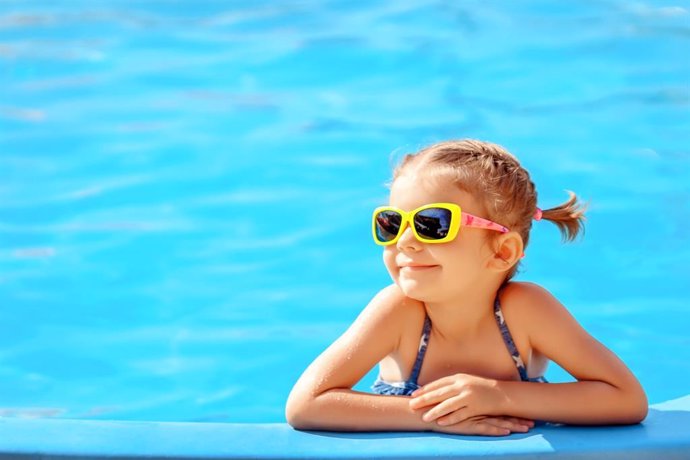 Archivo - Niña con gafas de sol en la piscina.