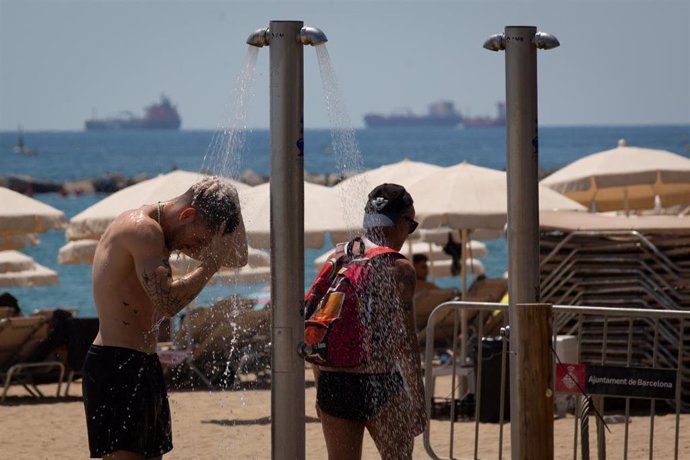 Varias personas se mojan en las duchas de la playa de la Barceloneta, a 13 de julio de 2022, en Barcelona, Catalunya (España). La intensa y extensa ola de calor llega hoy a su momento cumbre, aunque ese pico se mantendrá durante varios días seguidos, se