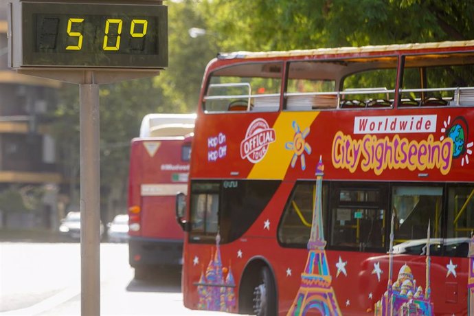 Un autobús turístico pasa sin pasajeros delante de un termómetro que marca 5O en otro día con altas temperaturas en la capital andaluza a 25 de julio del 2022 en Sevilla (Andalucía, España)