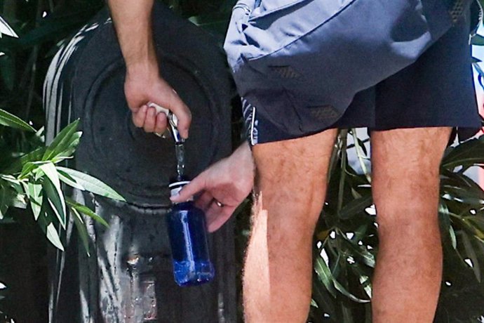 Una persona rellena una botella de agua en una fuente