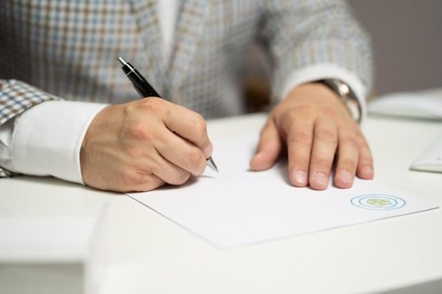 Imagen de archivo de una persona firmando unas solicitudes