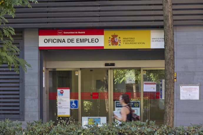 Varias personas pasan por delante de una oficina de empleo.