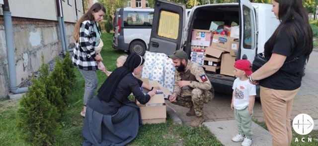 Una religiosa en Ucrania junto a desplazados reciben paquetes de ayuda.