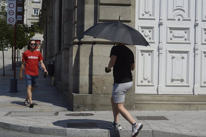 Una persona camina por la calle con paraguas en plena ola de calor.