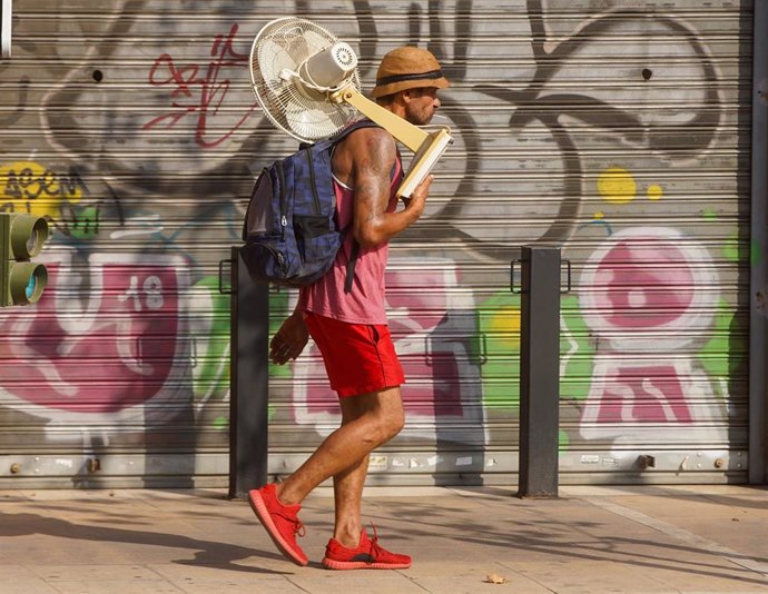 Un hombre con un ventilador por la calle. 