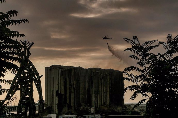 Un helicóptero deja caer agua sobre los devastados silos de trigo del puerto de Beirut después de que una parte de ellos se derrumbara justo cinco días antes del segundo aniversario de la explosión masiva del 4 de agosto de 2020 que arrasó el puerto 
