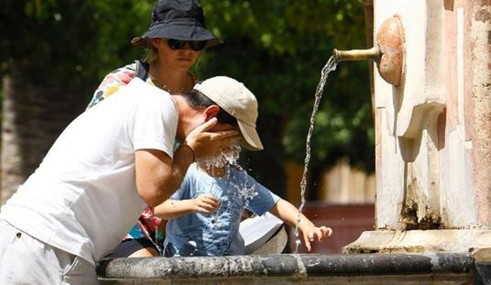 Turistas se refrescan en una fuente.