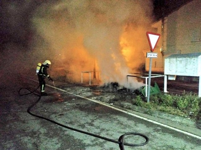 Los bomberos apagan las llamas de los contenedores quemados