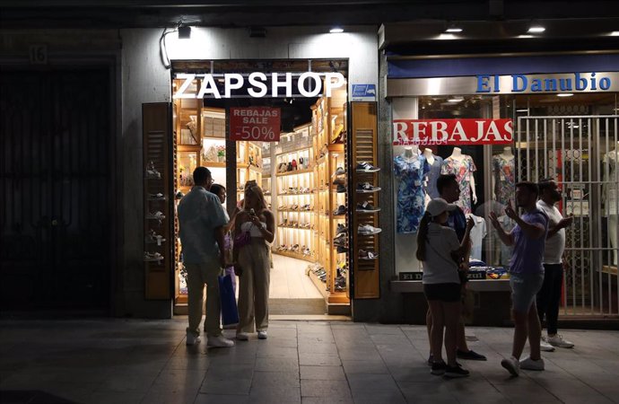 Varias personas en las puertas de una tienda, en Madrid (España). 