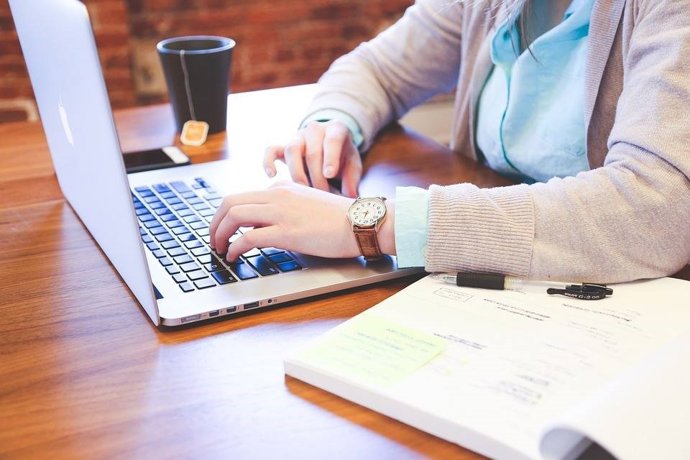 Archivo - Una persona treballant amb un ordinador porttil