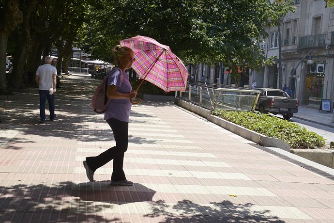 Una mujer camina por una vía en plena ola de calor, a 12 de julio de 2022, en Orense, Galicia (España). Los termómetros de la práctica totalidad del territorio gallego alcanzarán valores extremos debido a la ola de calor que comenzó la semana pasada y