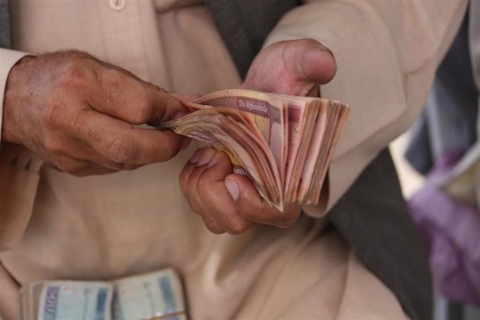 Un hombre cuenta efectivo en un mercado de cambio de dinero en Kabul, Afganistán