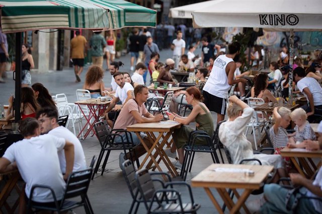Varias personas sentadas en terrazas en la plaza dels Àngels del Raval, a 4 de agosto de 2022, en Barcelona, Cataluña (España). El Ayuntamiento de Barcelona ha avanzado una hora el cierre de restaurantes, venta alimentaria y terrazas en la calle de Joaqui