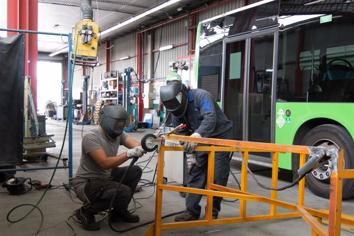 Dos personas trabajando junto a un bus de la EMT Palma.