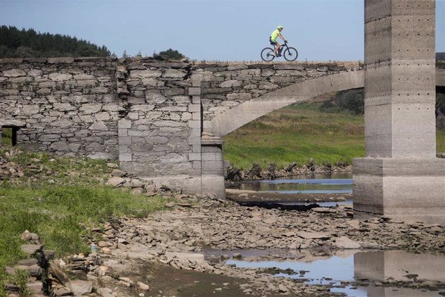 Un ciclista pasa por encima del viejo puente sobre el Miño, sepultado por las aguas en 1962 y visible cuando el cauce transcurre muy bajo, a 27 de julio de 2022, en Lugo, Galicia, (España). La costa gallega lleva en prealerta por sequía meteorológica desd
