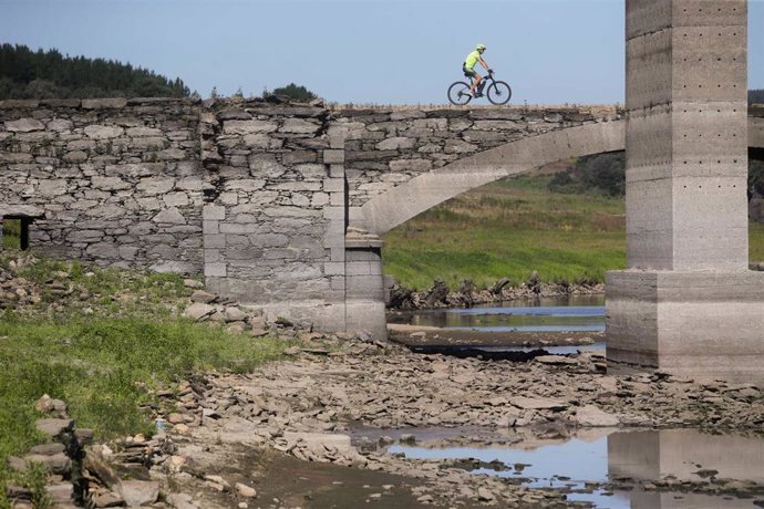 Un ciclista pasa por encima del viejo puente sobre el Miño, sepultado por las aguas en 1962 y visible cuando el cauce transcurre muy bajo, a 27 de julio de 2022, en Lugo, Galicia, (España). La costa gallega lleva en prealerta por sequía meteorológica de