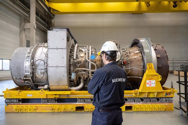 03 August 2022, North Rhine-Westphalia, Muelheim: A Siemens employee stands in front of the turbine serviced in Canada for the Nordstream 1 natural gas pipeline. Photo: Bernd Thissen/dpa
