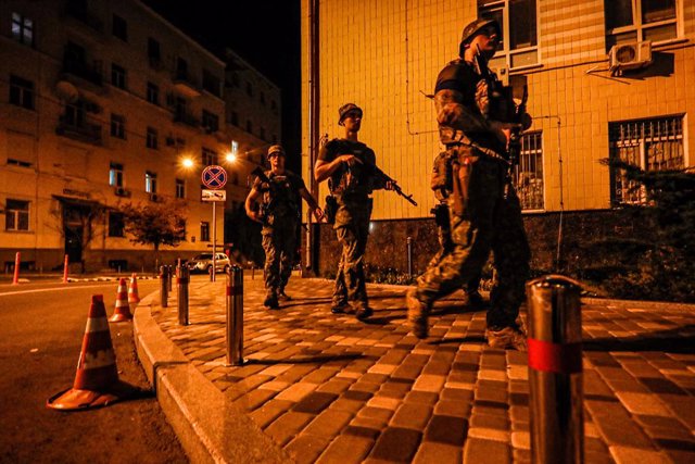 31 July 2022, Ukraine, Kiev: Four Ukrainian soldiers from a special unit walk across a crosswalk and patrol the streets of Kiev near foreign embassies during curfew to eliminate possible threats to diplomats and representatives in Ukraine and to investiga