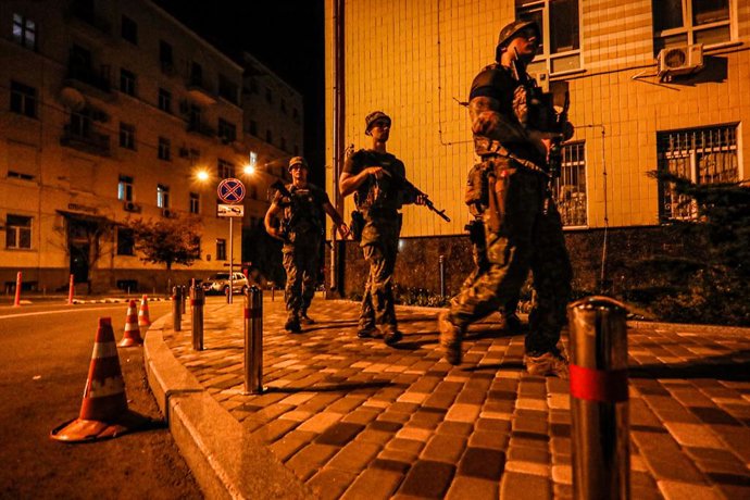 31 July 2022, Ukraine, Kiev: Four Ukrainian soldiers from a special unit walk across a crosswalk and patrol the streets of Kiev near foreign embassies during curfew to eliminate possible threats to diplomats and representatives in Ukraine and to investi