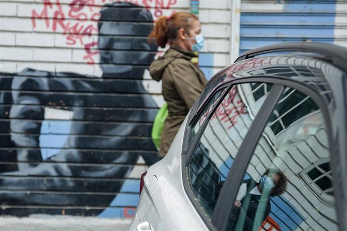 Archivo - Una mujer en una fila para recoger alimentos donados por una asociación.