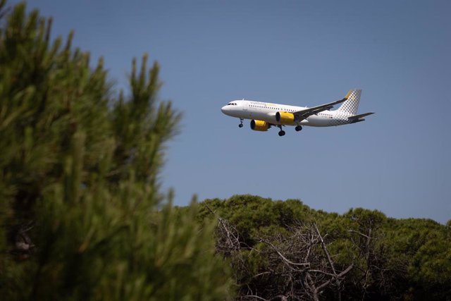 Archivo - Un avión sobrevuela el Aeropuerto de Barcelona