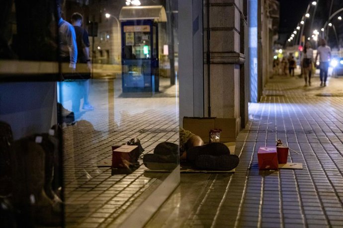 Archivo - Una persona duerme a las puertas de una zapatería durante la realización del censo de personas en situación de sinhogarismo llevado a cabo por la fundación Arrels, a 15 de junio de 2022, en Barcelona, Cataluña (España). Desde 2016, Arrels real