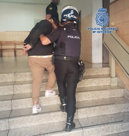 Un agente de la Policía Nacional conduce al detenido al interior de la comisaría