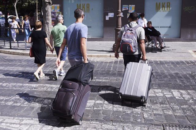 Archivo - Dos turistas, con maletas, cruzan un paso de peatones a 21 de junio de 2022 en Sevilla (Andalucía, España)