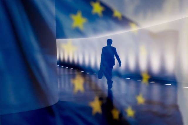 Archivo - Reflejo de una persona junto a una bandera de la Unión Europea (UE)