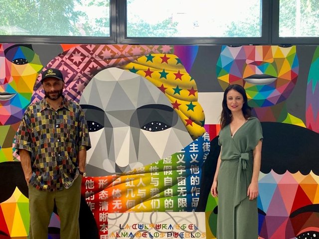 La delegada de Cultura, Turismo y Deportes del Ayuntamiento de Madrid, Andrea Levy, junto al miembro del equipo del artista callejero Okuda San Miguel, Nacho Blumen, en el mural de la Biblioteca Pública Municipal de San Fermín, en Usera (Madrid).