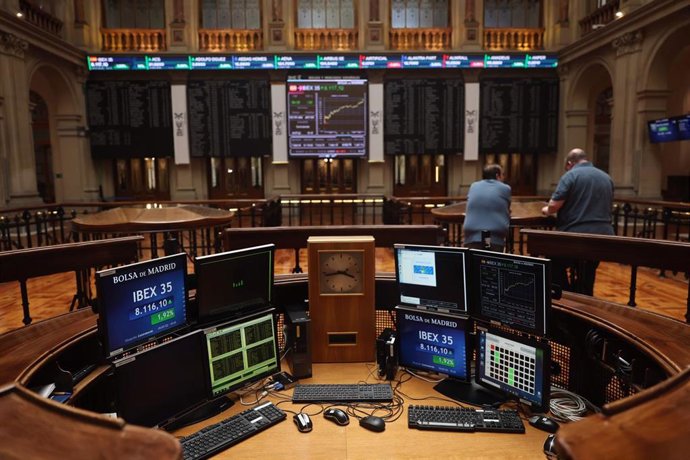 Dos personas miran los paneles del Palacio de la Bolsa, a 19 de julio de 2022, en Madrid (España). 