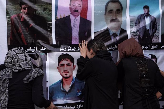 Los yazidíes reaccionan emocionados ante una pancarta con las fotos de las víctimas mientras participan en un acto en el templo de Lalish para conmemorar el octavo aniversario del genocidio yazidí llevado a cabo por la organización Estado Islámico en Si