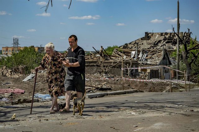 Archivo - Una mujer y su hijo caminan por una zona arrasada en Donetsk.