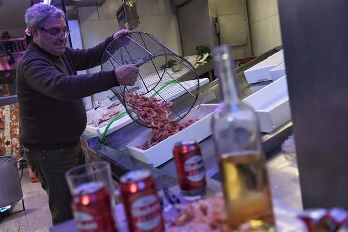 Archivo - Un pescadero madrileño coloca el marisco en una pescadería, a 23 de diciembre de 2021, en Madrid (España). Preparar el marisco mediante cocido forma parte de la cultura gastronómica de la Navidad.