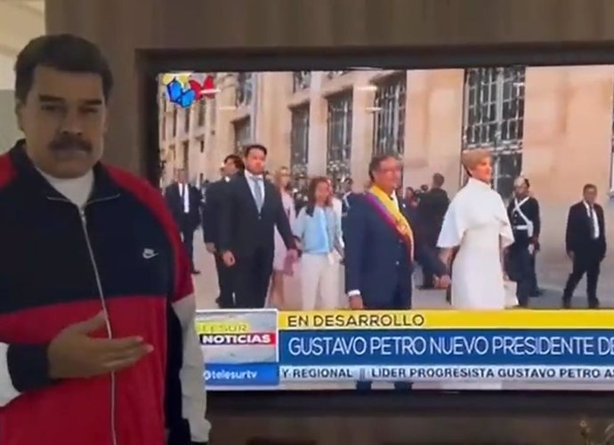 El presidente de Venezuela, Nicolás Maduro, junto a una imagen de televisión de la toma de posesión del presidente de Colombia, Gustavo Petro