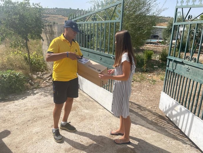 Un cartero rural de Correos repartiendo un paquete.