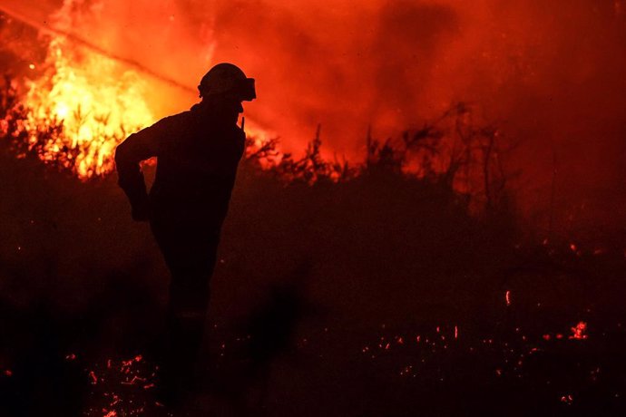 11 August 2022, France, Belin-Beliet: A firefighter walks past the flames of a forest fire near Belin-Beliet. French officials have warned that the forest fire could spread further in the southwest of the country. Photo: Thibaud Moritz/AFP/dpa