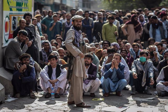 Archivo - Un miliciano talibán guarda la cola para retirar dinero en Kabul, Afganistán